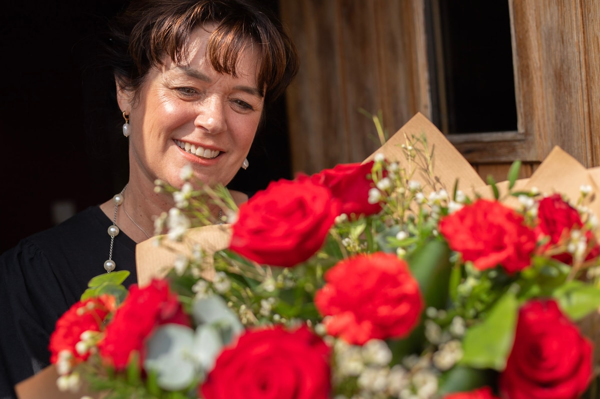 Woman receiving classic bouquet of red roses at the door, same day delivery by florist in Ireland